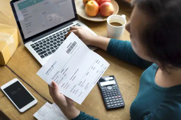 Femme devant ordinateur avec facture à la main pour facturation électronique