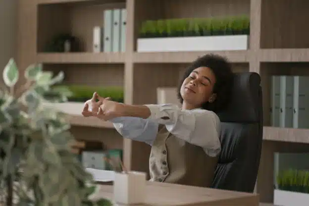 une femme détendue s'étire assise à son bureau
